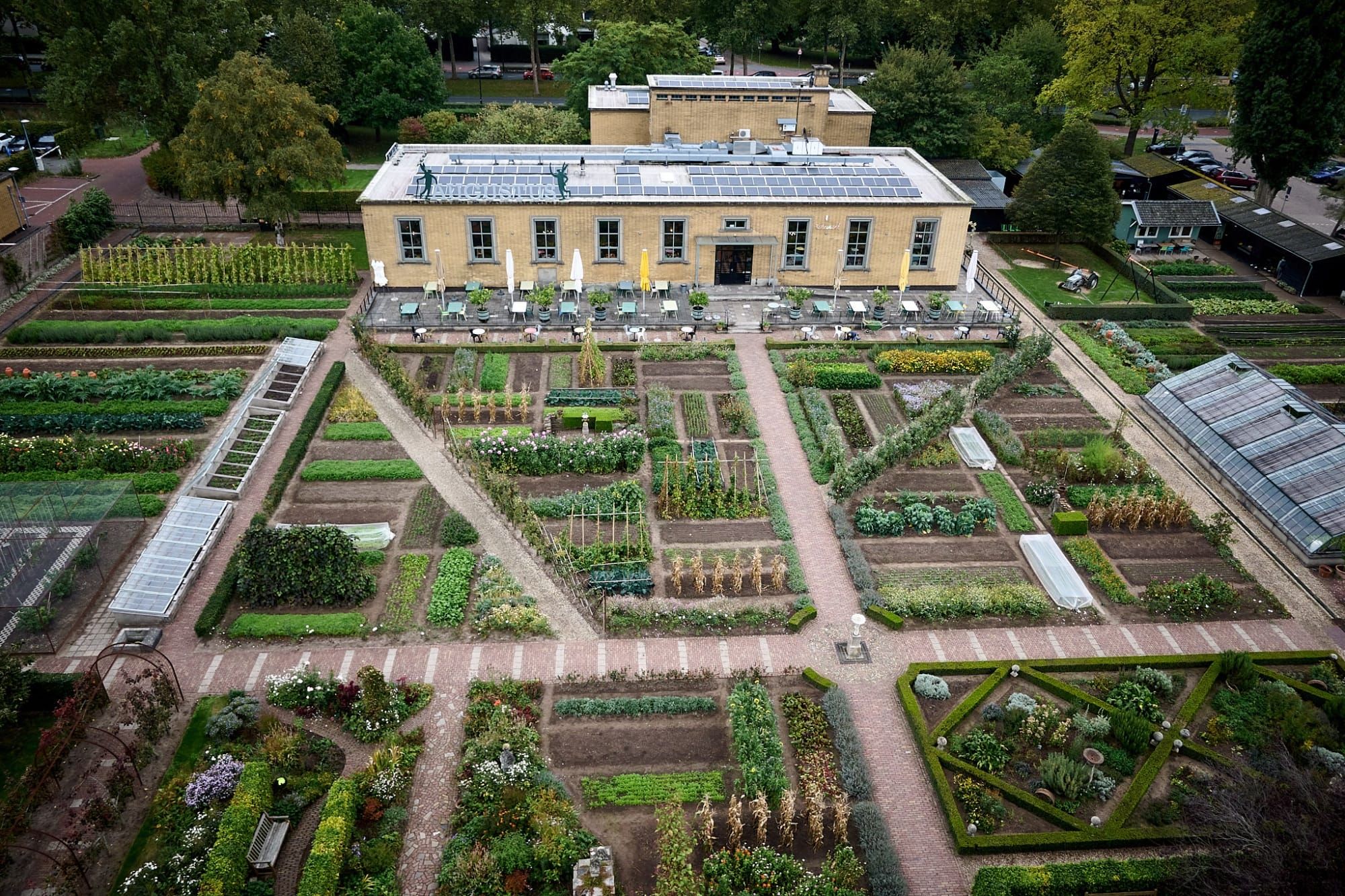 Aerial view of botanical garden with geometric beds, yellow Hortus building and solar panels