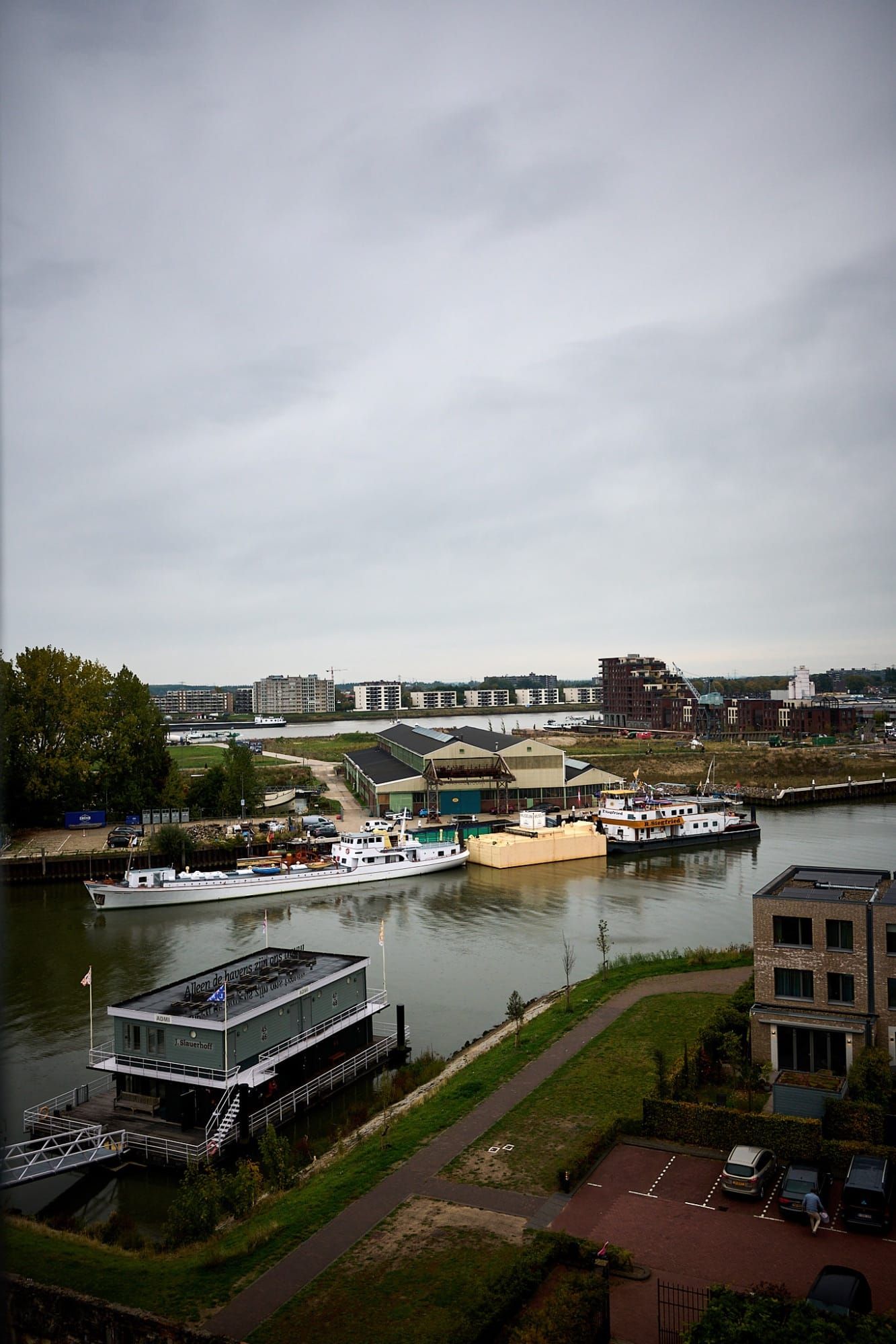Elevated view of canal with boats, barges and apartment buildings under cloudy sky