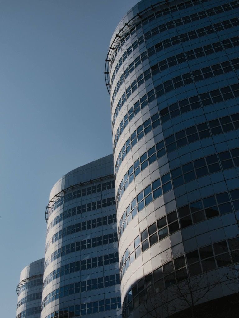 Curved glass office towers against a clear blue sky