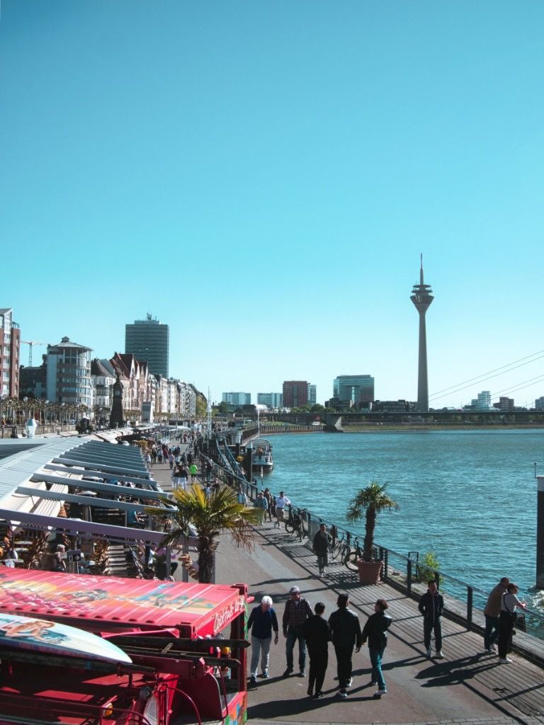 Riverside promenade along the Rhine in Dusseldorf with the Rheinturm in the background under a clear blue sky