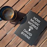 A book on the table next to a blue coffee mug, the book title is How music works